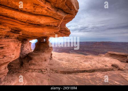 Un micro arco sul bordo del canyon al Dead Horse Point state Park con il Canyonlands National Park dietro. Moab, Utah. Foto Stock