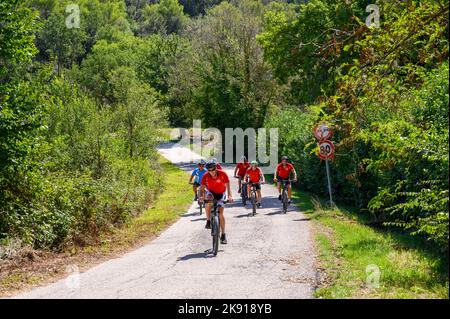 Un gruppo di ciclisti norvegesi di mezza età in bicicletta noleggiata percorrendo una strada collinare nel paesaggio umbro vicino a Spoleto, Umbria, Italia. Foto Stock