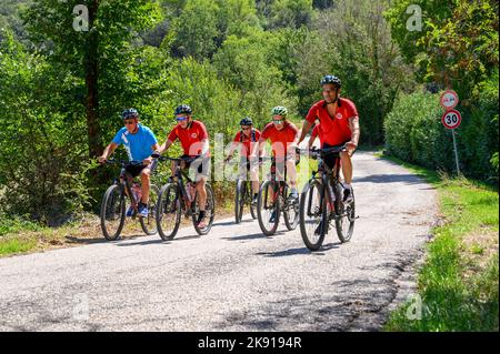 Un gruppo di ciclisti norvegesi di mezza età in bicicletta noleggiata percorrendo una strada collinare nel paesaggio umbro vicino a Spoleto, Umbria, Italia. Foto Stock