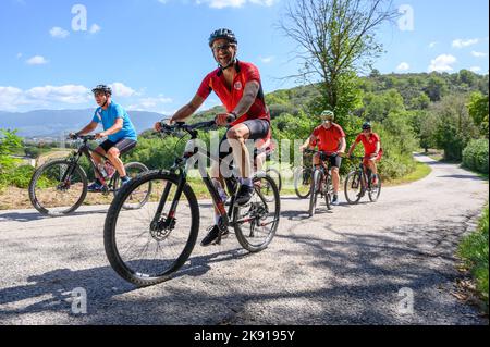 Un gruppo di ciclisti norvegesi di mezza età in bicicletta noleggiata percorrendo una strada collinare nel paesaggio umbro vicino a Spoleto, Umbria, Italia. Foto Stock