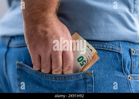 mano dell'uomo che tiene 50 banconote di euro nella tasca posteriore dei jeans Foto Stock