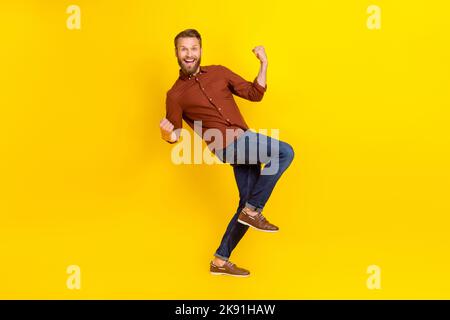 Foto a grandezza naturale di un bell'uomo impressionato bionda barba borgogna camicia clench pugni ggridare yeah isolato su sfondo di colore giallo Foto Stock