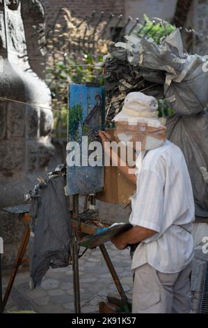 Uno scatto verticale di un gentleman asiatico senior dipinge un quadro sulle strade di Palma, Spagna Foto Stock