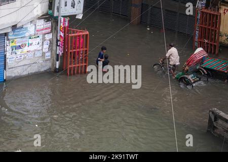 Dhaka, Bangladesh. 25th Ott 2022. I proprietari di risciò lottano per attraversare una strada bagnata a seguito di forti piogge causando molta sofferenza per pedoni e pendolari. Cyclone Sitrang colpisce il Bangladesh strappando comunicazioni e collegamenti elettrici, inondando le strade portando le attività a uno stand fermo. (Credit Image: © Sazzad Hossain/SOPA Images via ZUMA Press Wire) Foto Stock