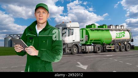 Uomo con tablet digitale su uno sfondo di camion con un serbatoio con l'iscrizione BIO Foto Stock