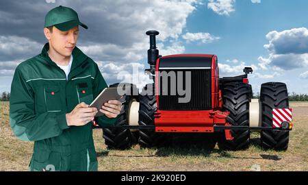 Un agricoltore con tavoletta digitale controlla un autonomo del trattore su una smart farm Foto Stock