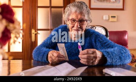 Vecchia donna disimballare il kit di prova di coronavirus a casa. La nonna caucasica ha fatto un test rapido a casa sua per Covid19. Quarantena nonna e pandemia co Foto Stock