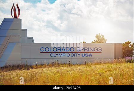 Segno di benvenuto della città olimpica degli Stati Uniti Colorado Springs circondato da erba gialla. Cielo nuvoloso in background. Foto Stock