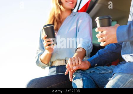 Giovane coppia uomo e donna che viaggiano insieme in auto nuova avendo sosta per bere caffè in un campo di grano al tramonto Foto Stock