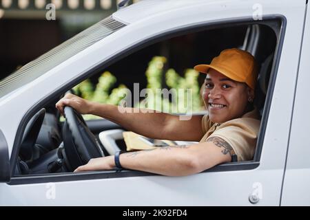 Immagine laterale di una donna che sorride alla telecamera dalla finestra del furgone Foto Stock