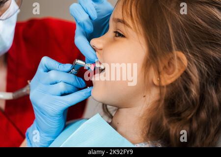 Il dentista del bambino fa la pulizia professionale dei denti in odontoiatria. Igiene professionale per i denti del bambino in odontoiatria. Il dentista pediatrico esamina e con Foto Stock