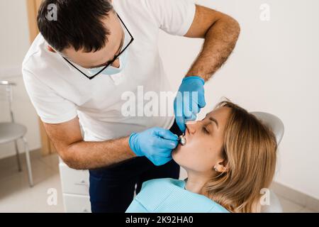 Il medico inserisce il vassoio per impronte e facendo il getto di denti al paziente in odontoiatria prima dell'impianto dentale. Procedura di creazione di protesi dentarie, c Foto Stock