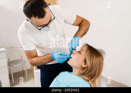 Il medico inserisce il vassoio per impronte e facendo il getto di denti al paziente in odontoiatria prima dell'impianto dentale. Procedura di creazione di protesi dentarie, c Foto Stock