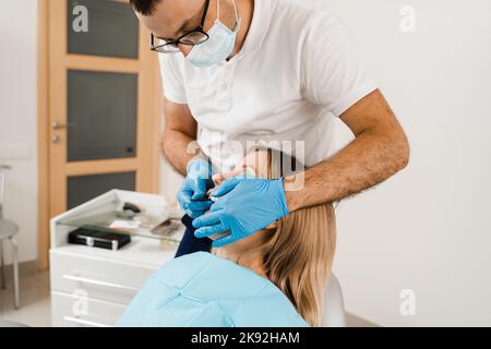 Procedura di creazione di protesi dentarie, corone e allineatori. Il medico inserisce il vassoio per impronte e facendo il getto di denti al paziente in odontoiatria prima d Foto Stock