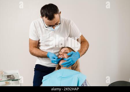 Il medico inserisce il vassoio per impronte e facendo il getto di denti al paziente in odontoiatria prima dell'impianto dentale. Procedura di creazione di protesi dentarie, c Foto Stock