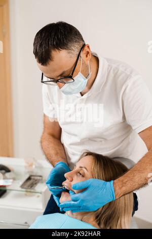 Il medico inserisce il vassoio per impronte e facendo il getto di denti al paziente in odontoiatria prima dell'impianto dentale. Procedura di creazione di protesi dentarie, c Foto Stock