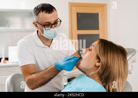 Il medico inserisce il vassoio per impronte e facendo il getto di denti al paziente in odontoiatria prima dell'impianto dentale. Procedura di creazione di protesi dentarie, c Foto Stock