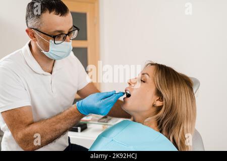 Il medico inserisce il vassoio per impronte e facendo il getto di denti al paziente in odontoiatria prima dell'impianto dentale. Procedura di creazione di protesi dentarie, c Foto Stock