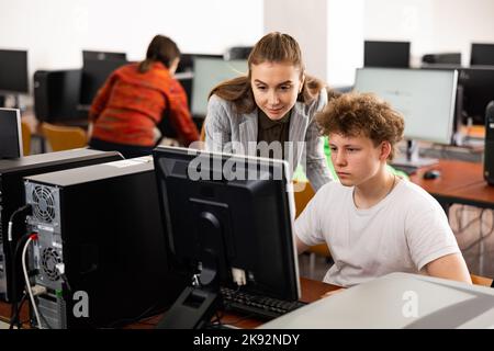 L'insegnante insieme agli studenti conduce una lezione sull'educazione informatica Foto Stock