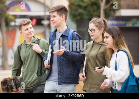 Gli studenti che camminano fuori dalla scuola sono spensierati Foto Stock