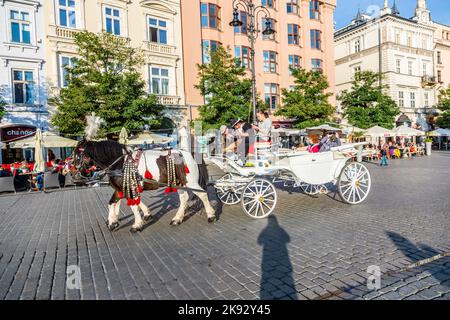 CRACOVIA, POLONIA - Oct 7, 2014: Carrozze a cavallo di fronte alla chiesa di Mariacki sulla piazza principale della città di Cracovia. Fare un giro a cavallo in una carrozza è molto pop Foto Stock