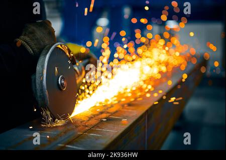 Laborer taglia travi metalliche con dischi abrasivi in officina Foto Stock