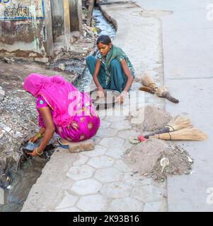 BIKANER, INDIA - 24 ottobre 2012: La donna cerca di trovare polvere d'oro nella canalizzazione della zona oro smith in Bikaner, India. Foto Stock