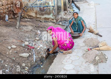 BIKANER, INDIA - 24 ottobre 2012: La donna cerca di trovare polvere d'oro nella canalizzazione della zona oro smith in Bikaner, India. Foto Stock