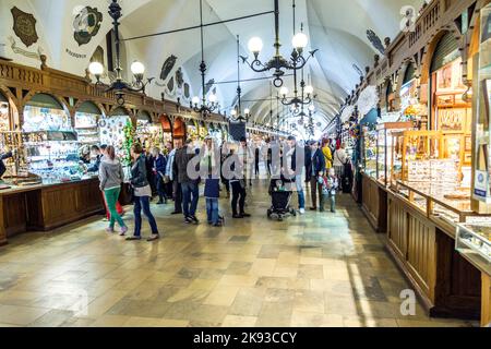 CRACOVIA, POLONIA - 4 MAGGIO: Persone in transito con bancarelle di souvenir artigianali della sala di stoffa gotica Sukiennice sulla piazza del mercato principale il 5 maggio, Foto Stock