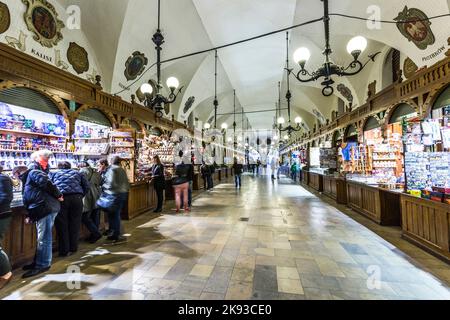 CRACOVIA, POLONIA - 4 MAGGIO: Persone in transito con bancarelle di souvenir artigianali della sala di stoffa gotica Sukiennice sulla piazza del mercato principale il 5 maggio, Foto Stock