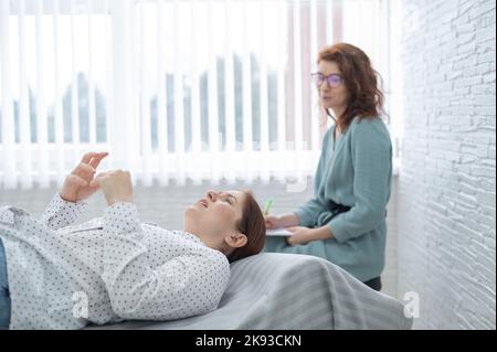 Una donna di mezza età si trova su un divano e parla con uno psicologo. Foto Stock