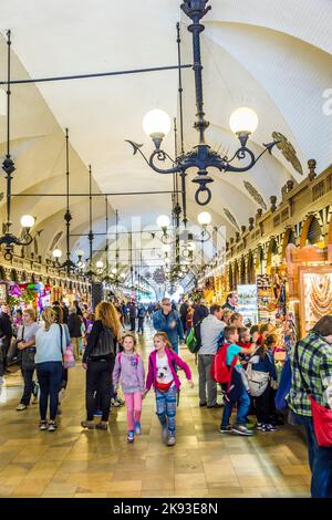 CRACOVIA, POLONIA - 7 SETTEMBRE 2014: Persone in passaggio con bancarelle di souvenir artigianali artistici della sala di stoffa gotica Sukiennice sulla piazza principale del mercato in K Foto Stock