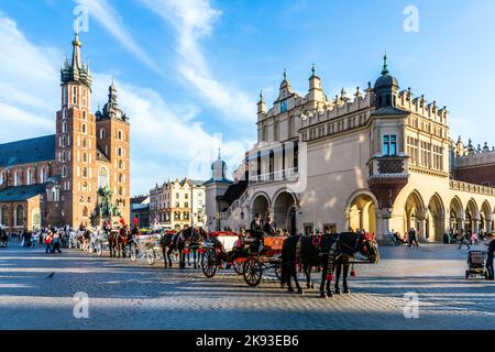 CRACOVIA, POLONIA - Oct 7, 2014: Carrozze a cavallo di fronte alla chiesa di Mariacki sulla piazza principale della città di Cracovia. Fare un giro a cavallo in una carrozza è molto pop Foto Stock