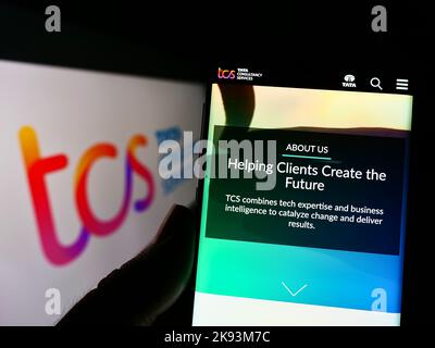 Persona che tiene il cellulare con il Web page della società indiana Tata Consultancy Services (TCS) sullo schermo con il logo. Messa a fuoco al centro del display del telefono. Foto Stock
