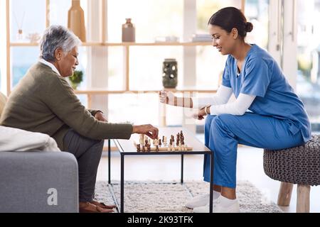 Theres sempre un elemento di divertimento al loro giorno. Una giovane infermiera che gioca a scacchi con una donna anziana in una casa di pensione. Foto Stock
