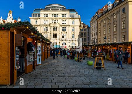 Le persone che camminano lungo la strada acciottolata tra chioschi di legno e mercatino di Natale a Vienna, Austria. Foto Stock