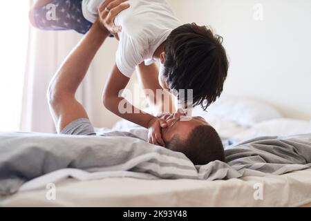 Condividiamo un legame speciale tra noi: Un padre e un figlio allegro che giocano insieme nella camera da letto di casa. Foto Stock