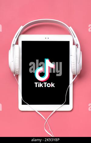 Bangkok, Thailandia. Ottobre 2022 Tablet Tik Tok applicazione icona, logo su schermo e cuffie wireless su sfondo colorato trendy social network concetto Flat Lay Top view. Foto Stock