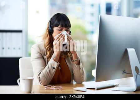 OH no, devo prendere l'influenza, una giovane donna d'affari attraente che soffre di un freddo e soffia il naso mentre si trova nel suo ufficio. Foto Stock