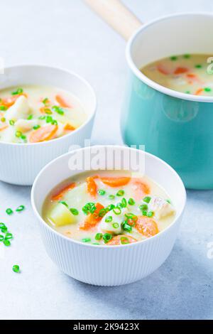 Zuppa di zuppa di merluzzo con piselli verdi, patate e carote in un recipiente bianco. Foto Stock