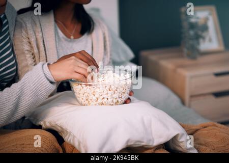 Lo spuntino migliore per quando ti senti come uno spuntino. Due donne irriconoscibili mangiano popcorn a casa. Foto Stock