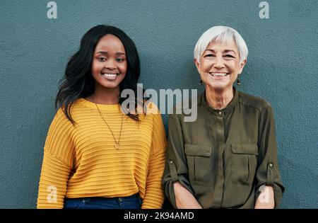 Lifes tutto circa imparare l'un l'altro. Ritratto di una giovane e giovane donna d'affari allegra che si posa insieme contro un muro all'aperto. Foto Stock