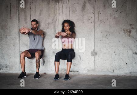 L'equilibrio è la chiave di tutto nella vita. Foto a tutta lunghezza di una giovane coppia sportiva che si esercita contro un muro all'interno di un parcheggio sotterraneo. Foto Stock