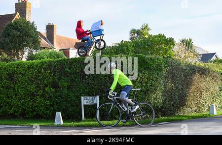 Worthing UK 26th ottobre 2022 - Un ciclista passa per lo scarecrow ET che è apparso volando sopra una siepe nel Festival annuale dello scarecro nel villaggio di Ferring vicino a Worthing , Sussex occidentale . Oltre 70 spaventapasseri sono attesi per comparire in tutto il villaggio nel corso della settimana : Credit Simon Dack / Alamy Live News Foto Stock