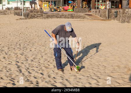 PLAYA BLANCA, SPAGNA - APRILE 2: Un uomo di governo pulisce la spiaggia a Aprile 2,2012 a Playa Blanca, Spagna. La spiaggia è artificiale e la sabbia è nave Foto Stock