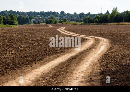 Strada sterrata tortuosa attraverso un campo agricolo Foto Stock