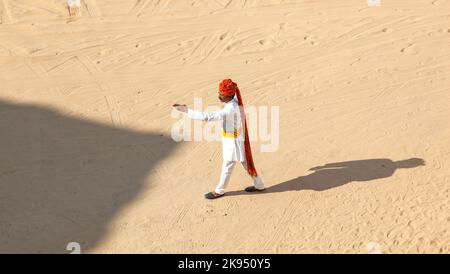 Mandawa, India - 25 ottobre 2012: Un cameriere del Rajasthani che indossa tradizionali turbanti colorati passa il parcheggio vuoto presso l'hotel nel deserto a Pushka Foto Stock