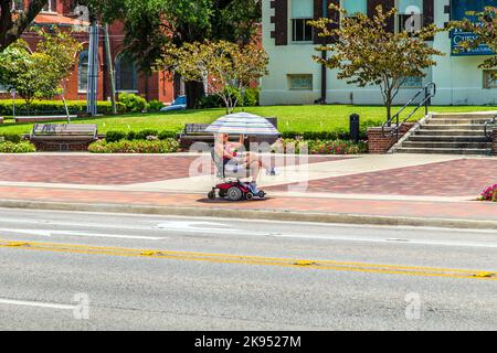 LAKE CHARLES, USA - 9 AGOSTO: Attrattiva donna in sedia a rotelle elettrica il 9 agosto 2013 a Lake Charles, USA. La sedia a rotelle elettrica è stata inventata Foto Stock