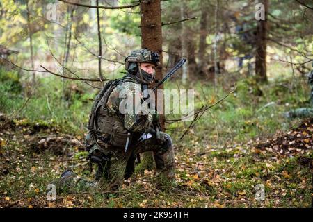 24 ottobre 2022, Estonia, Ämari: Un soldato della Bundeswehr si accola in una zona boscosa durante un esercizio presso la base aerea di Ämari. Le unità navali e aeree stanno praticando la protezione delle infrastrutture critiche sul fianco orientale della NATO durante la manovra della Tigre Baltica 2022 in Estonia. Foto: Christophe Gateau/dpa Foto Stock