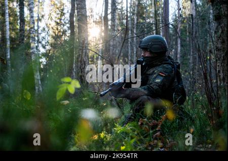 24 ottobre 2022, Estonia, Ämari: Un soldato della Bundeswehr si accola in una zona boscosa durante un esercizio presso la base aerea di Ämari. Le unità navali e aeree stanno praticando la protezione delle infrastrutture critiche sul fianco orientale della NATO durante la manovra della Tigre Baltica 2022 in Estonia. Foto: Christophe Gateau/dpa Foto Stock